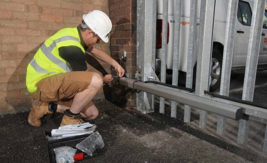 A heavy-duty linear gate operator is installed on a wooden swing gate, connected to a control box. This type of system is commonly used in residential driveways for secure and automated access.