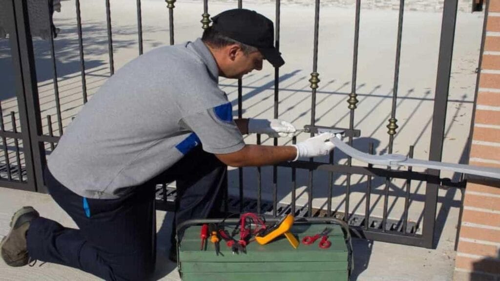 Technician repairing a metal automatic gate with toolset.