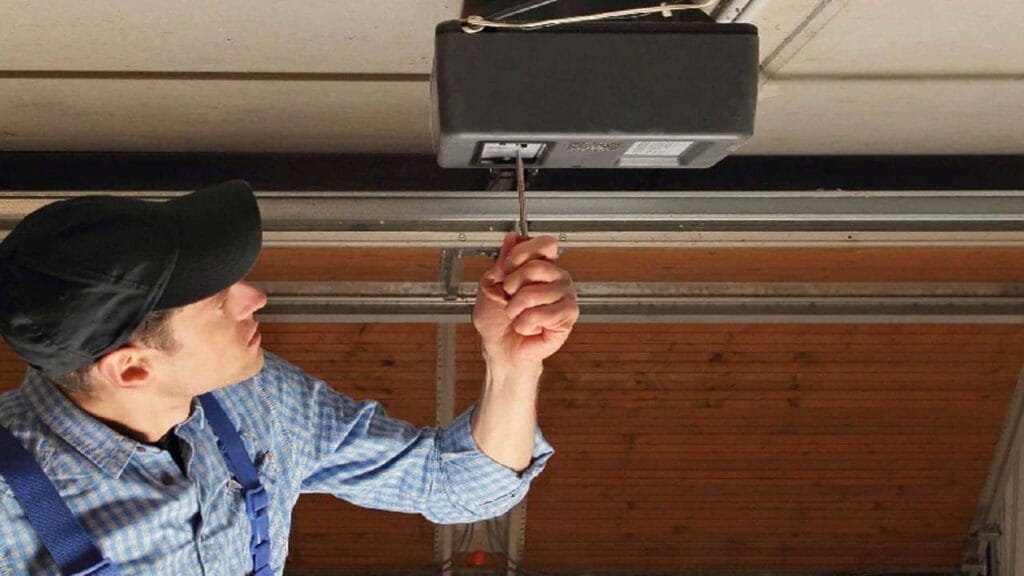 Gate technician adjusting a ceiling-mounted garage gate motor with a screwdriver.