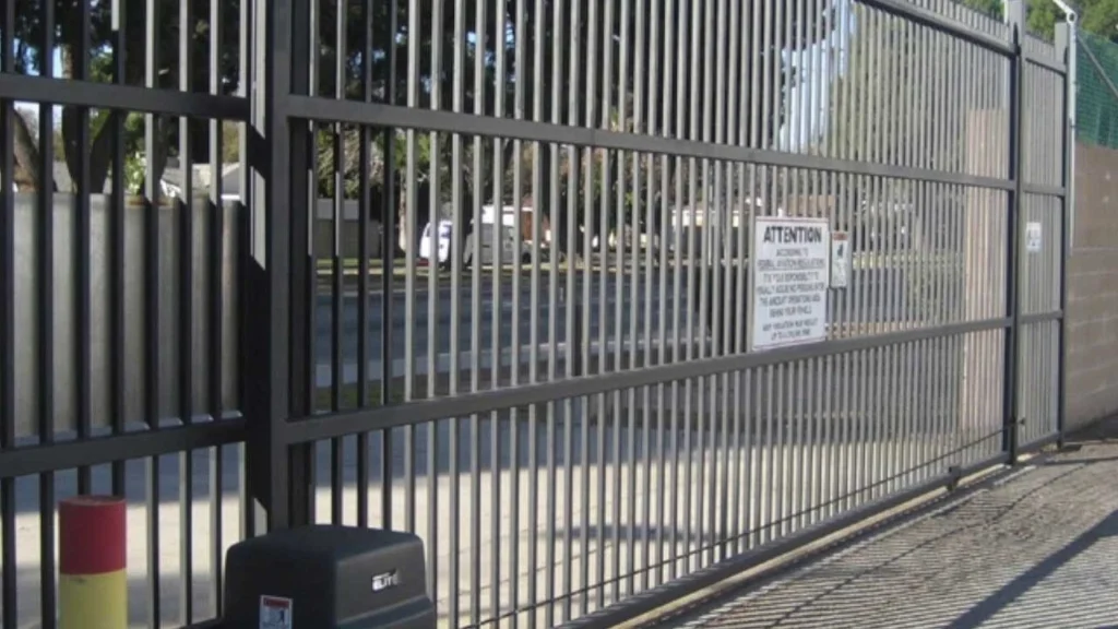 Industrial sliding security gate with warning sign by Professional Gate Replacement in Austin TX
